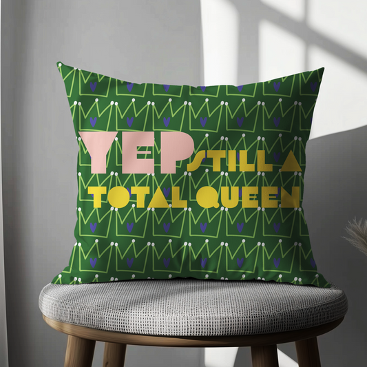 Green cushion cover with a repeating crown pattern and bold text reading “Yep, still a total queen” in pink and yellow—perfect for bold, empowering home décor.