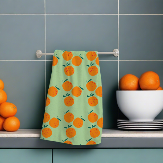 a green coloured with a orange design cotton tea towel hanging on a rail 