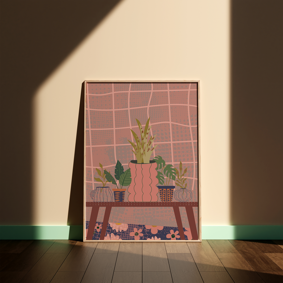 A framed art print featuring a stylized illustration of potted plants on a table against a pink grid background, leaning against a beige wall on a wooden floor with dramatic sunlight and shadow.