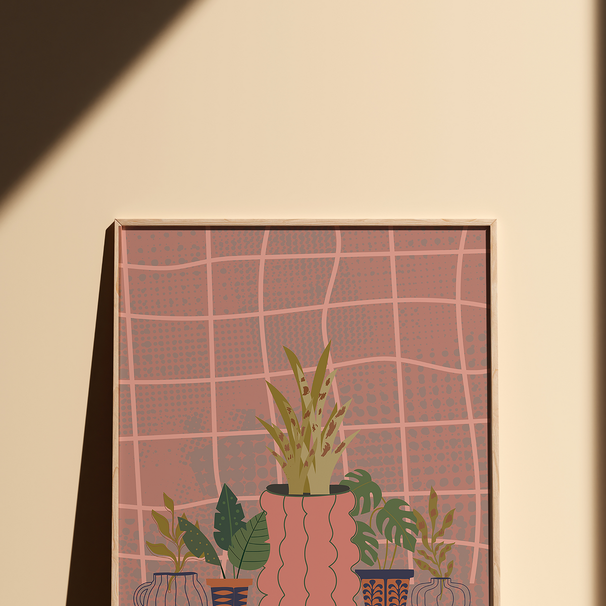 A framed art print featuring a stylized illustration of potted plants against a pink grid background, displayed on a beige wall with a strong diagonal shadow.